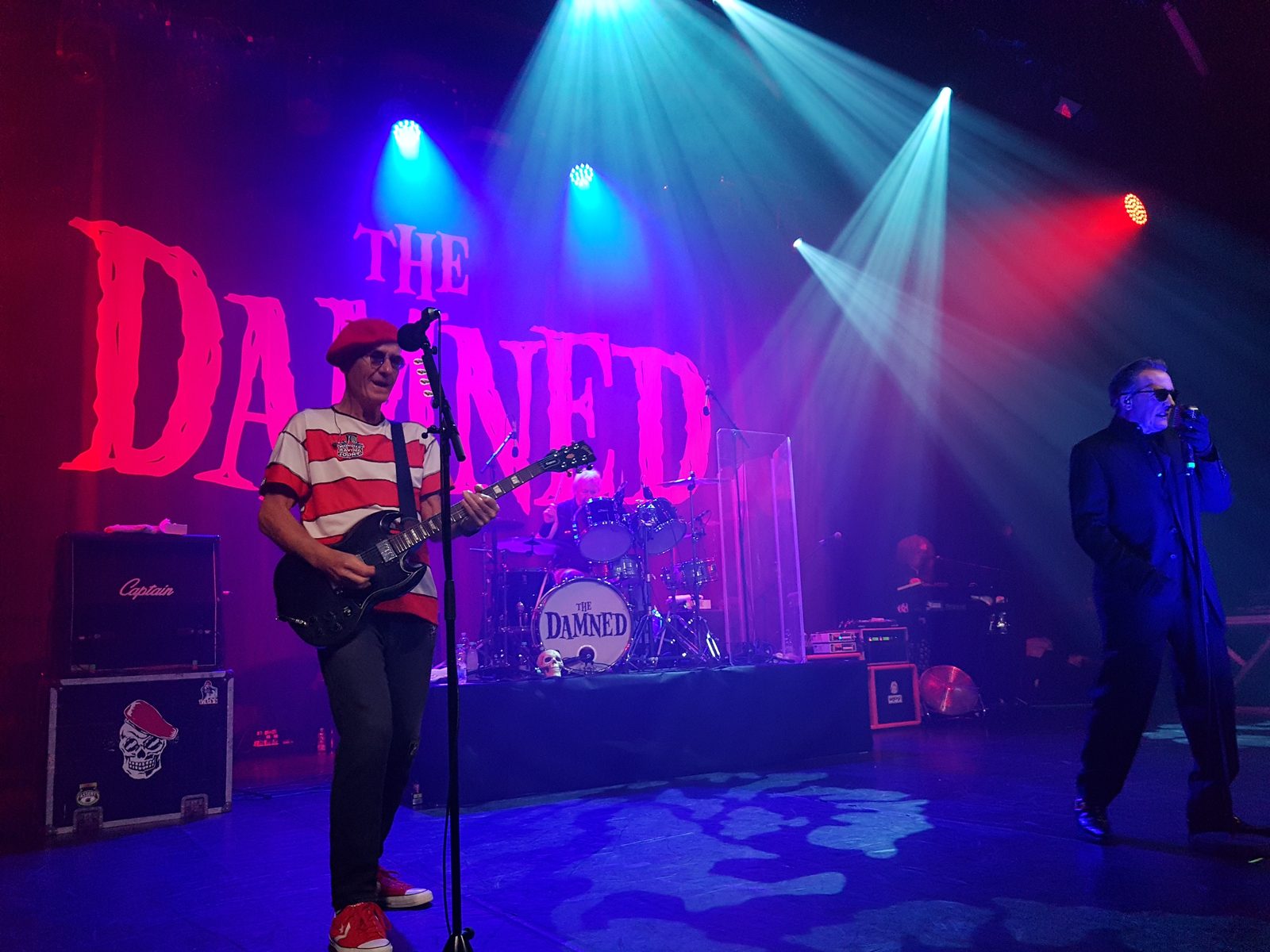 Captain Sensible with his guitar, in a red beret and a striped shirt