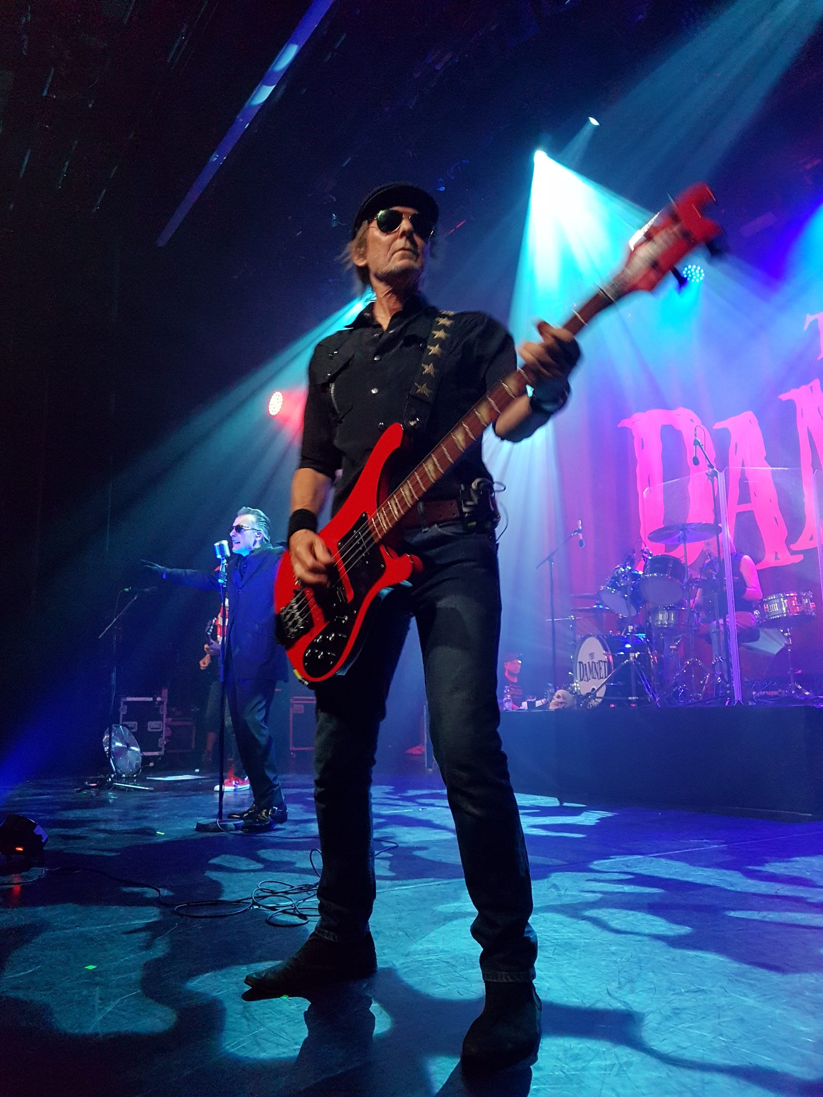 A bassist with a red bass, in a hat and sunglasses
